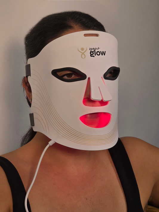 Person wearing a LED face mask with visible branding on a plain background