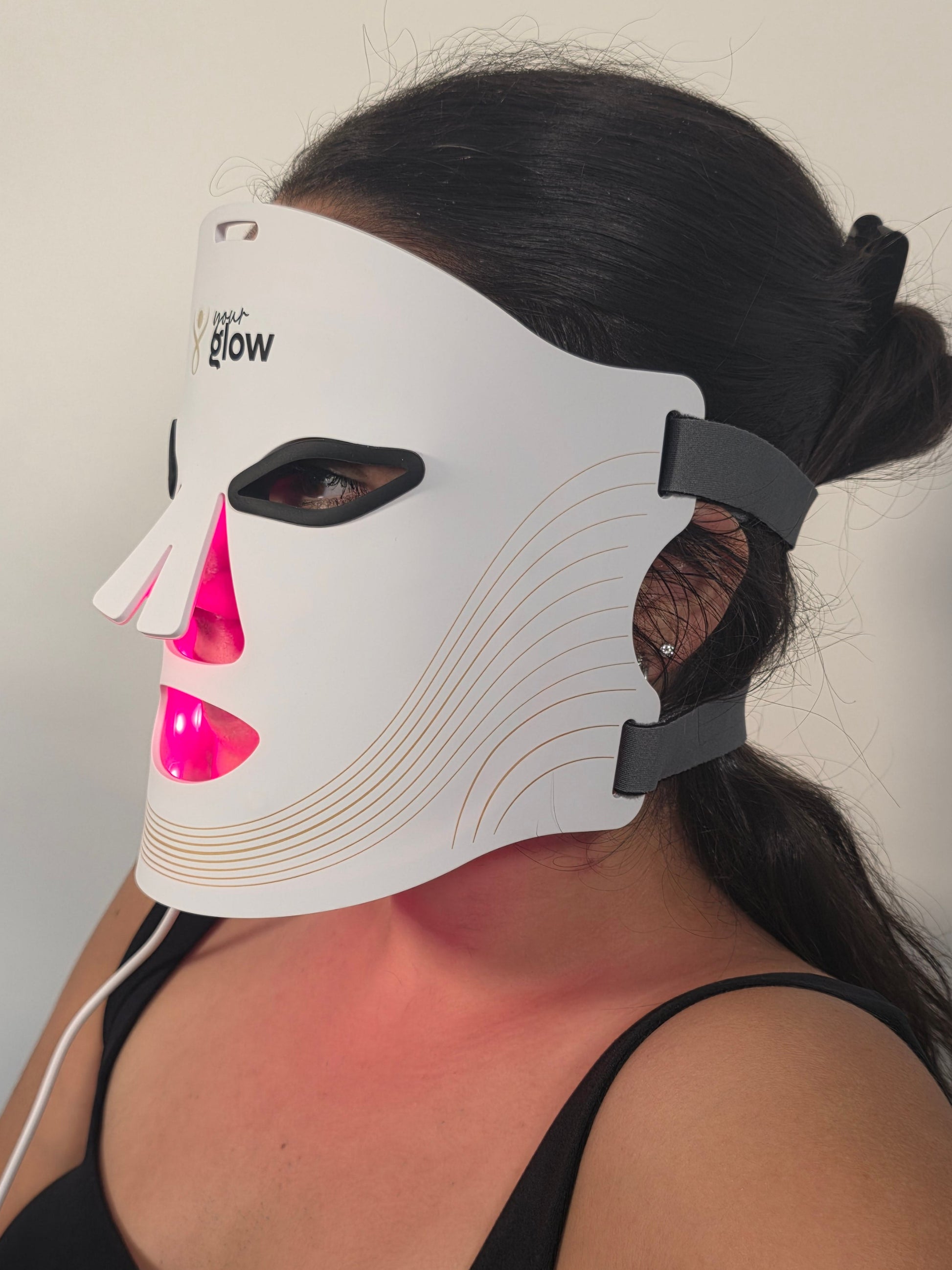 Person wearing a white LED face mask with Red light therapy on a plain background